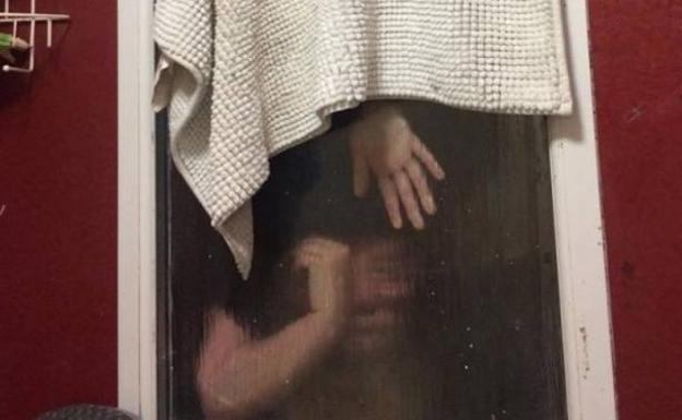 Foto de la chica encajada en el doble cristal del baño