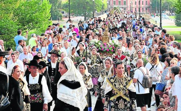 Integrantes de la Asociación del Traje Charro cruzan el Puente Romano con la talla de la Virgen de la Vega.