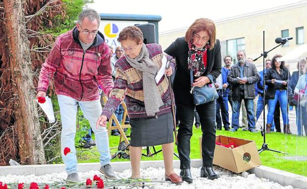 Dos de las asistentes al acto depositan un clavel rojo encima de una de las siluetas del memorial ‘Los 143’. /Antoraz