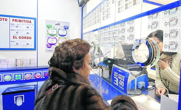 Una mujer es atendida en la administración de lotería situada en la Calle Mayor, en el entorno del Monumento a la Mujer. /Antonio Quintero