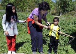 Un niño aprende a coger la azada para cavar en el huerto./ Ricardo Otazo/