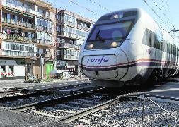 Un tren cruza el paso a nivel de Pilarica mientras un vehículo espera con la barrera bajada. :: Andrea Breiz/