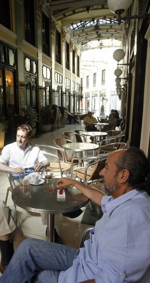 Los clientes toman el café 'sin humos' en la terraza del Pigiama. Sus mesas (derecha) tienen pegatinas desde el lunes advirtiendo de la prohibición, al igual que el resto de bares del Pasaje Gutiérrez :: A. Q. Y R. O./