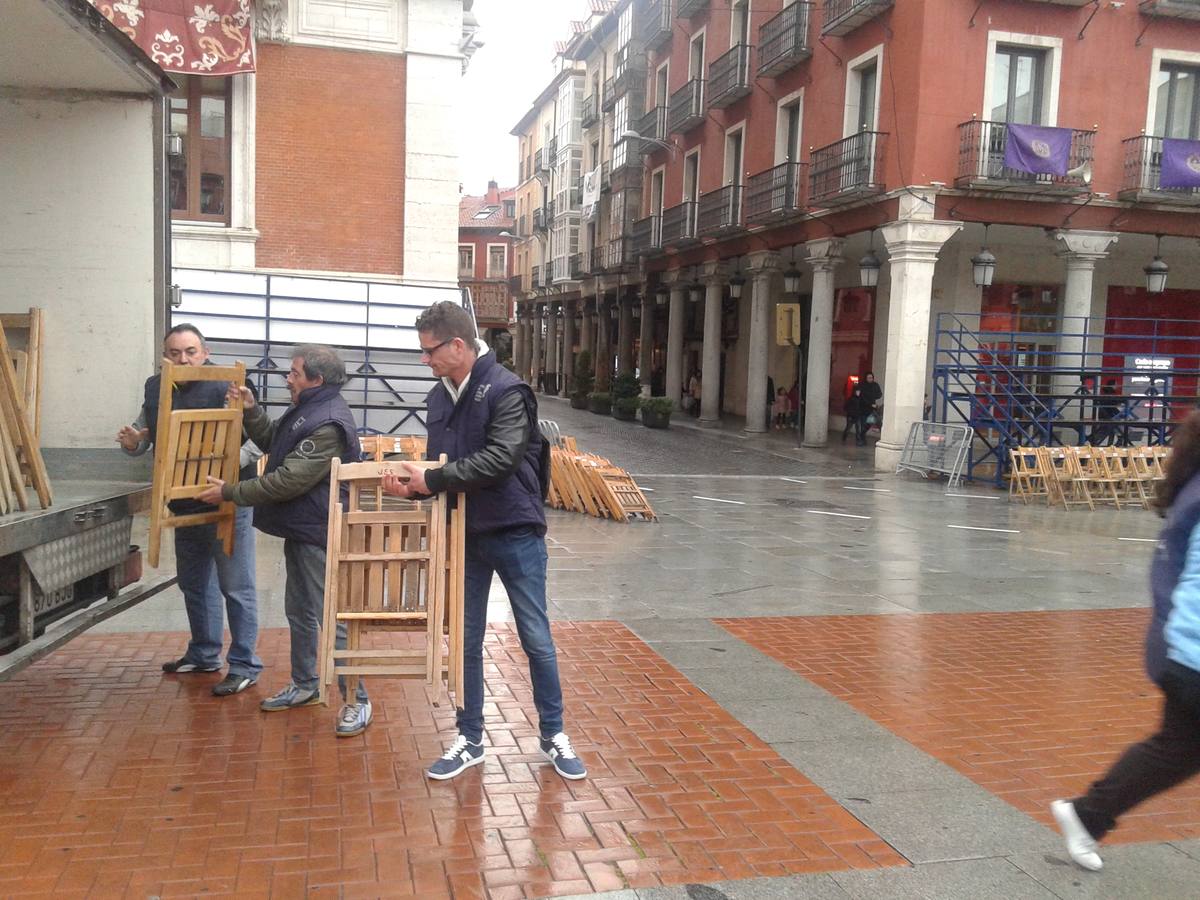 Operarios retiran las sillas de la Plaza Mayor de Valladolid colocadas para la Procesión General suspendida por la lluvia