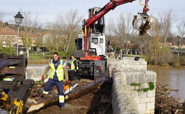 Tres camiones, una grúa y una retroexcavadora para retirar los troncos y la maleza del puente de Simancas