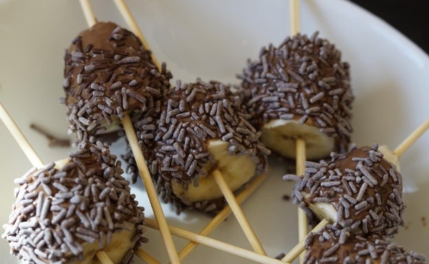 Pinchos de frutas cubiertos de chocolate con topping al gusto